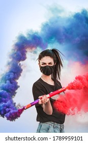 Girl In Protective Mask With Red And Blue Smoke Bombs. Sending Emergency Smoke Signal. Coronavirus, COVID-19 