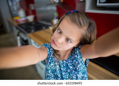 Girl Pulling Funny Faces In Kitchen At Home