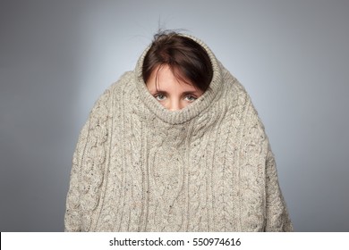 Girl pulls a large knitted sweater over her head. Despair and loneliness of depressed person