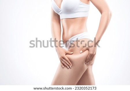 Girl pulls the skin on the abdomen and on the hips showing the body fat. Treatment and disposal of excess weight, the deposition of subcutaneous fat.