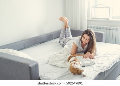 The girl with the puppy in bed. - Shutterstock ID 592649891