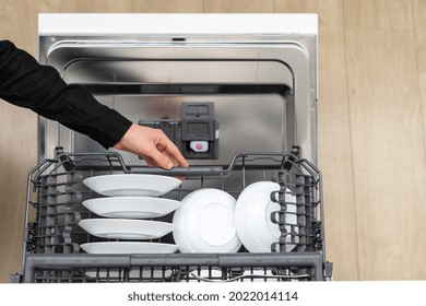 Girl Pushing In Drawer Full Of Tableware, White Plates And Bowls Inside Of Dishwasher, Cleaning Chemical Ready In Slot Of Open Dishwashing Machine Door With Tablet Compartment, Cropped Shot