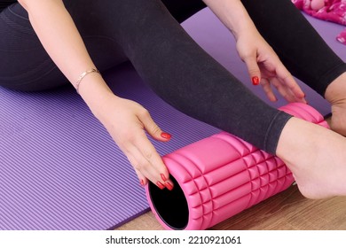 The Girl Puts A Foam Roller Under Her Leg For A Fitness Massage. Legs Close Up. Pregnant Yoga Practice Concept