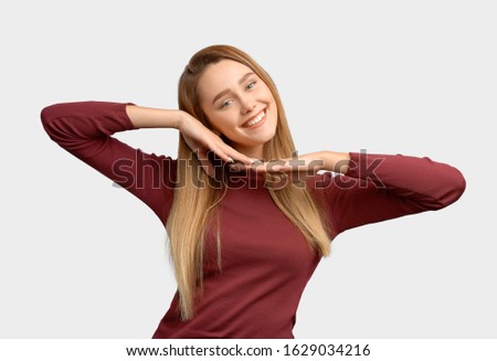 Girl puts head on hands, shows pretty face, snow-white smile. Beautiful young woman with long hair, clean smooth skin wears Burgundy-colored jacket sleeves isolated on white background in Studio