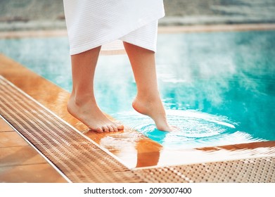 A girl puts her foot in a pool with hot thermal water, a wellness vacation at hot springs. - Powered by Shutterstock