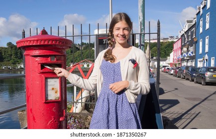 A Girl Puts A Letter In A Mailbox