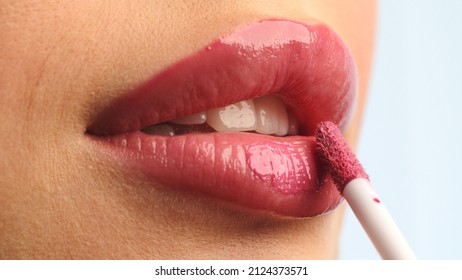 Girl puts lipstick on her lips with a brush. Close-up of women's lips and makeup brush.  Woman making makeup applying lipstick on a lip. Professional makeup.  Making maya. - Powered by Shutterstock