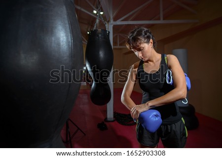 Girl puts on Boxing gloves in the sport gym. Sports, training, motivation, active lifestyle concept.