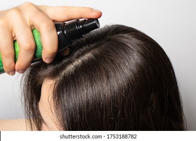 The girl puts on her hair a tonic of hydrolyte from a bottle. Hair care at home. - Shutterstock ID 1753188782