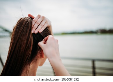 Girl putting bobby pins in hair outdoors. Close-up.