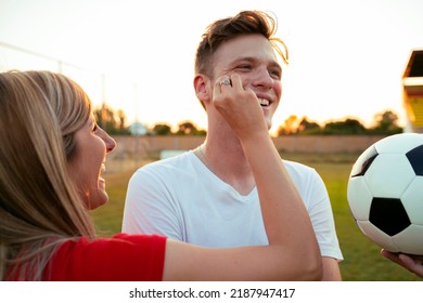 Girl Putting On Face Paint To Soccer Fan, Pre Match Preparation 