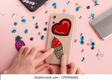 Girl Putting Red Heart And Ice Cream Patches Onto Beige Phone Case. Trendy DIY Project For Kids.