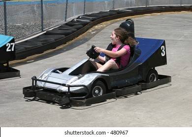 A Girl Racing A Go Cart Around A Racecourse