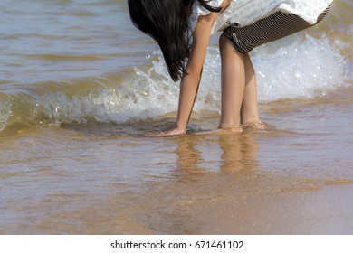 A Girl Reaching Down And Soaking Hand In The Sea