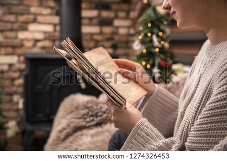 girl reading a book in a cozy home atmosphere near the fireplace, the concept of home rest close-up