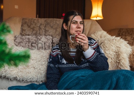 A girl reading book at home in cosy blanket while drinking hot coffee