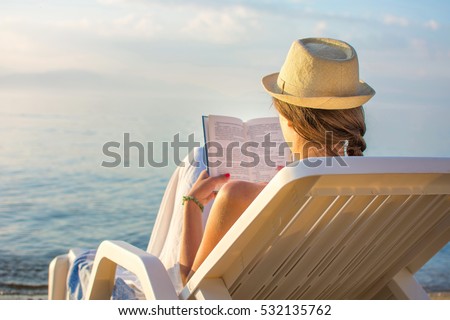 Girl reading a book in sunbed at the beach