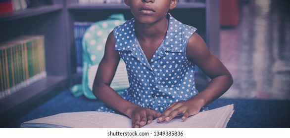 Girl reading braille book while sitting in library - Powered by Shutterstock