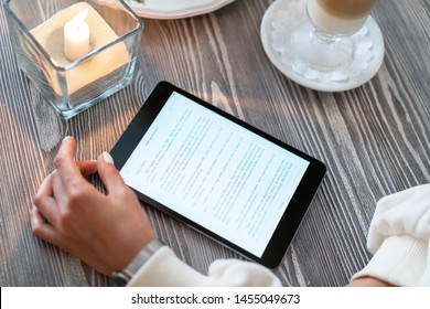 Girl Reading E-book At Breakfast In A Cafe. Read The Text From The Tablet Computer At A Table In A Cozy Restaurant. Traction Reading Knowledge