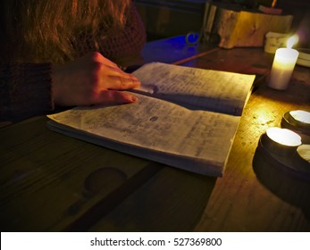 Girl Reading A Guestbook Diary In Candle Light. 