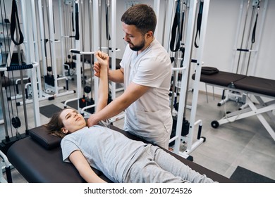 Girl Receive Shoulder Manual Therapy From Physiotherapist Man In Recovery Clinic. Sport Injury Rehab