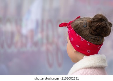 A Girl In A Red Bandana (scarf) On Her Head And A Light Jacket.