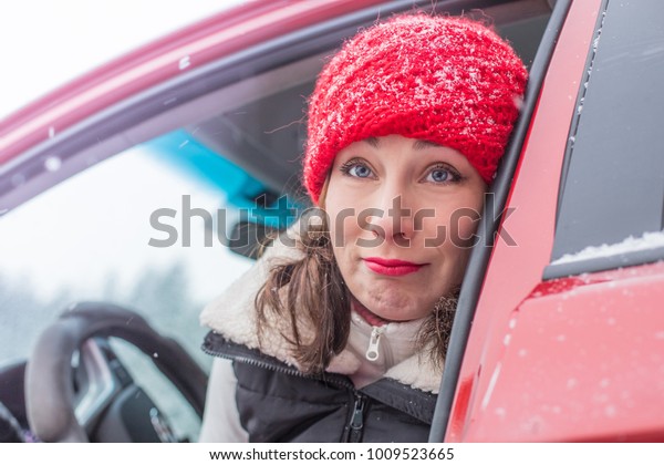 Girl in a red cap and warm jacket in a red car in\
a winter forest
