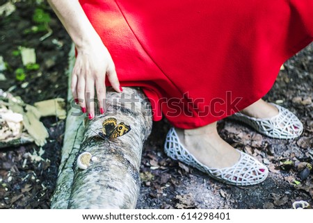 Girl in red dress with big butterfly in the forest