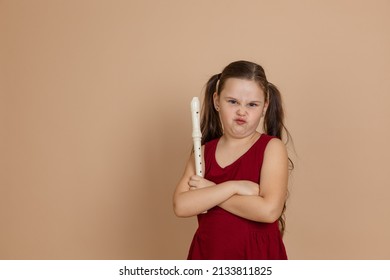 Girl in red dress with displeased grimace hold flute with arms crossed, beige background. Learning to play woodwind musical instrument. Flute and children is concept of music education development. - Shutterstock ID 2133811825
