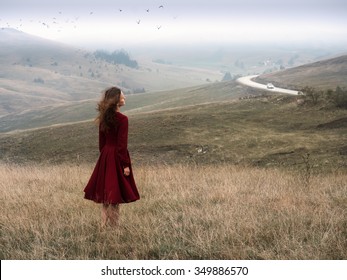 The girl in a red dress standing in the early misty morning in the endless hills in Zlatibor (Serbia ) . In the sky flying flock of birds and on the road lonely car rides - Powered by Shutterstock