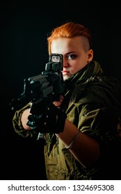 Girl with red hair, takes aim at the sight of machinegun in military uniform. Vertical background
