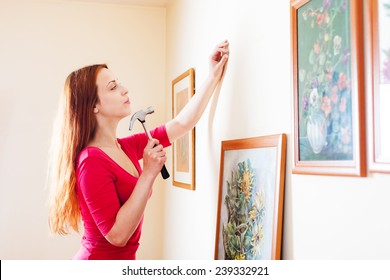 Girl In Red Hanging  Pictures In Frames On Wall At House