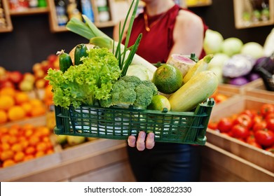 Girl in red holding different vegetables on fruits store. - Powered by Shutterstock