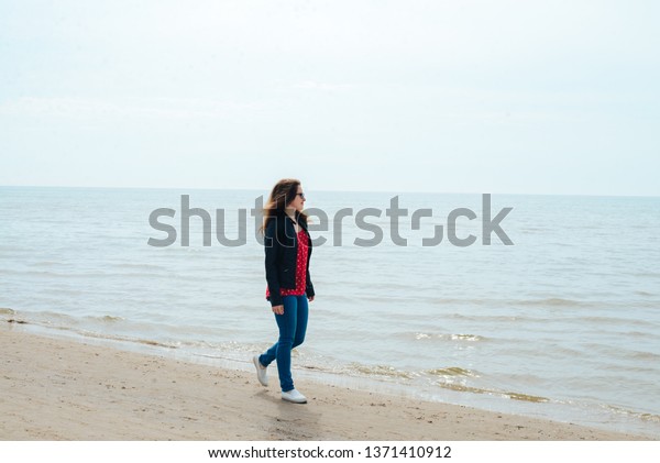 Girl in\
a red vest and leather jacket against the\
sea
