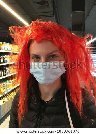 Girl in red wig and medical mask in the supermarket