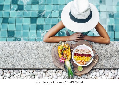 Girl Relaxing And Eating Fruit Plate By The Hotel Pool. Exotic Summer Diet. Tropical Beach Lifestyle.