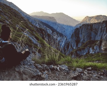a girl relaxing in front of a purple sunset in the middle of the mountains, with the silhouette in the background. peace and freedom.
