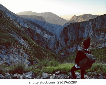 a girl relaxing in front of a purple sunset in the middle of the mountains, with the silhouette in the background. peace and freedom.