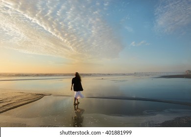 Girl relaxing on the beach at sunrise, beautiful cloudy sky reflected on the beach, pier in the background, Jacksonville, Florida, USA.  - Powered by Shutterstock