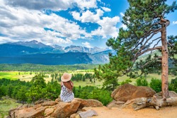 Girl Relaxing On The Rock On Hiking Trip In The Beautiful Park. Woman Sitting Looking At Summer Mountain View. Rocky Mountain National Park, Estes Park, Colorado, USA.