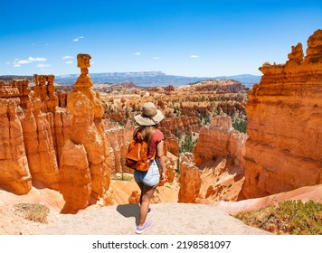 Girl relaxing on vacation hiking trip. Woman standing next to Thor's Hammer hoodoo on top of  mountain looking at beautiful view. Bryce Canyon National Park, Utah, USA