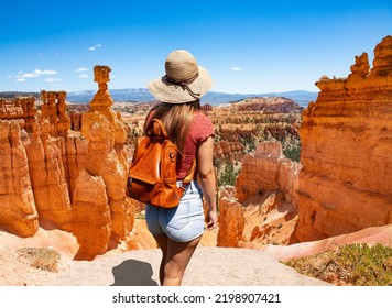 Girl Relaxing On Vacation Hiking Trip. Woman Standing Next To Thor's Hammer Hoodoo On Top Of  Mountain Looking At Beautiful View. Bryce Canyon National Park, Utah, USA