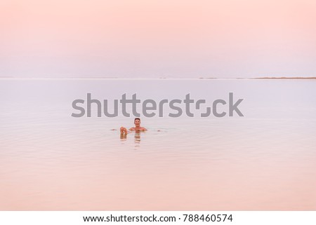 Girl relaxing in the water of Dead Sea at sunset