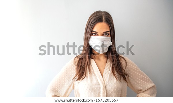Girl in respiratory mask. Masked woman looks at\
camera. Cold, flu, virus, tonsillitis, respiratory disease,\
quarantine, epidemic concept. Beautiful caucasian young woman with\
disposable face mask