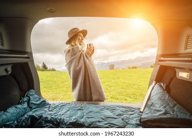 Girl Resting In Her Car. Woman Hiker, Hiking Backpacker Traveler Camper In Sleeping Bag, Relaxing, Drinking Hot Tea On Top Of Mountain. Road Trip. Health Care, Authenticity, Sense Of Balance Calmness.