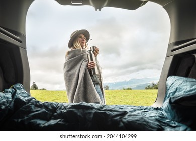 Girl Resting In Her Car. Woman Hiker, Hiking Backpacker Traveler Camper In Sleeping Bag, Relaxing, Drinking Hot Tea On Top Of Mountain. Road Trip. Health Care, Authenticity, Sense Of Balance Calmness.