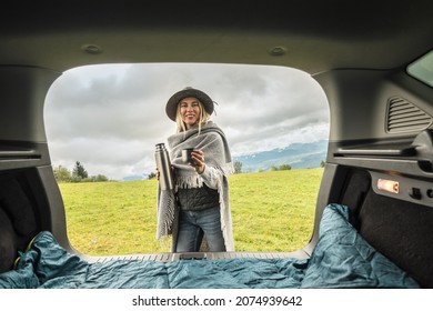 Girl Resting In Her Car. Woman Hiker, Hiking Backpacker Traveler Camper In Sleeping Bag, Relaxing, Drinking Hot Tea On Top Of Mountain. Road Trip. Health Care, Authenticity, Sense Of Balance Calmness.