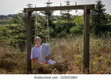 A girl resting on a swing in a garden on a beautiful summerday in Denmark