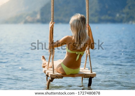 
Girl resting on a swing in the sea