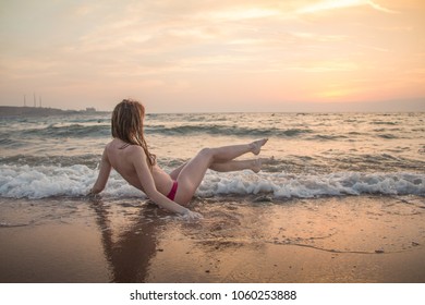 Girl rests and has fun in sea wave at sunset in the evening